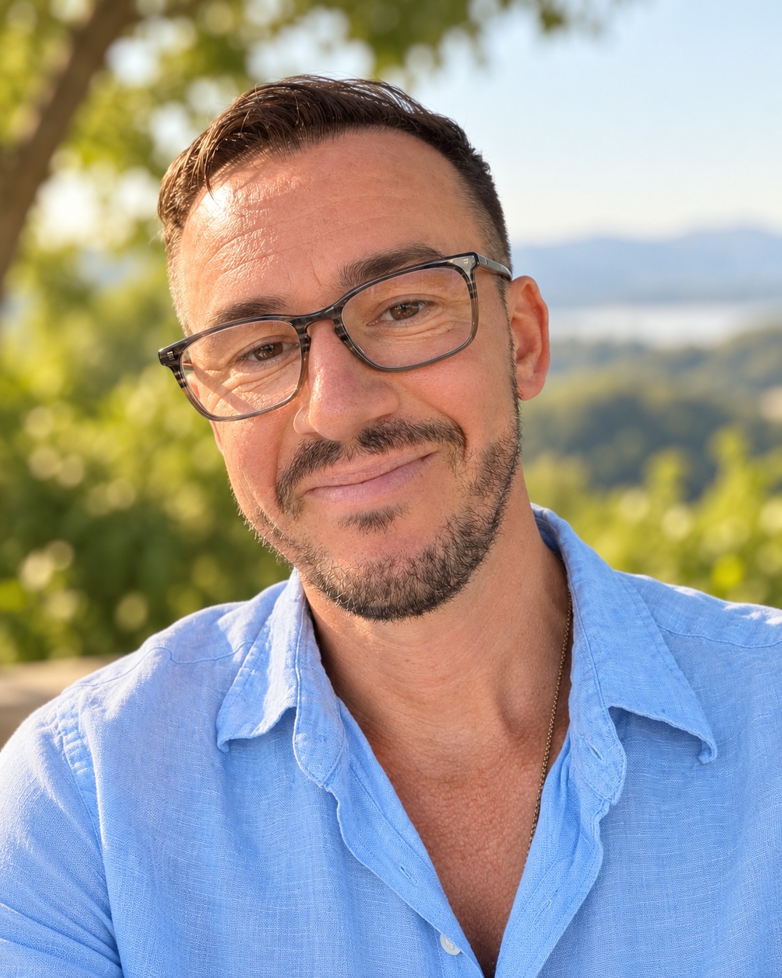 Dustan Drake wearing a blue collared shirt outdoors in a peaceful natural setting.